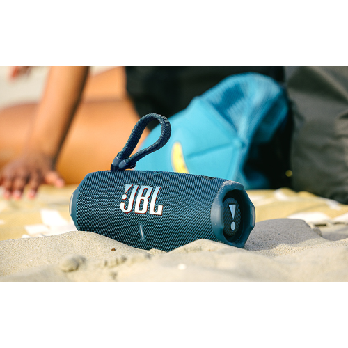 Blue JBL speaker on sand with people in the background