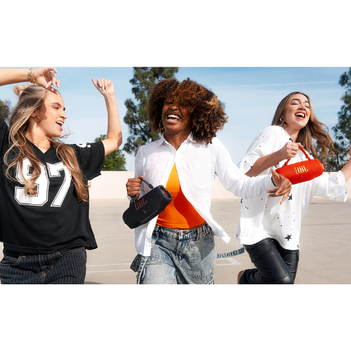 Three women laughing outdoors with a clear blue sky and trees in the background.