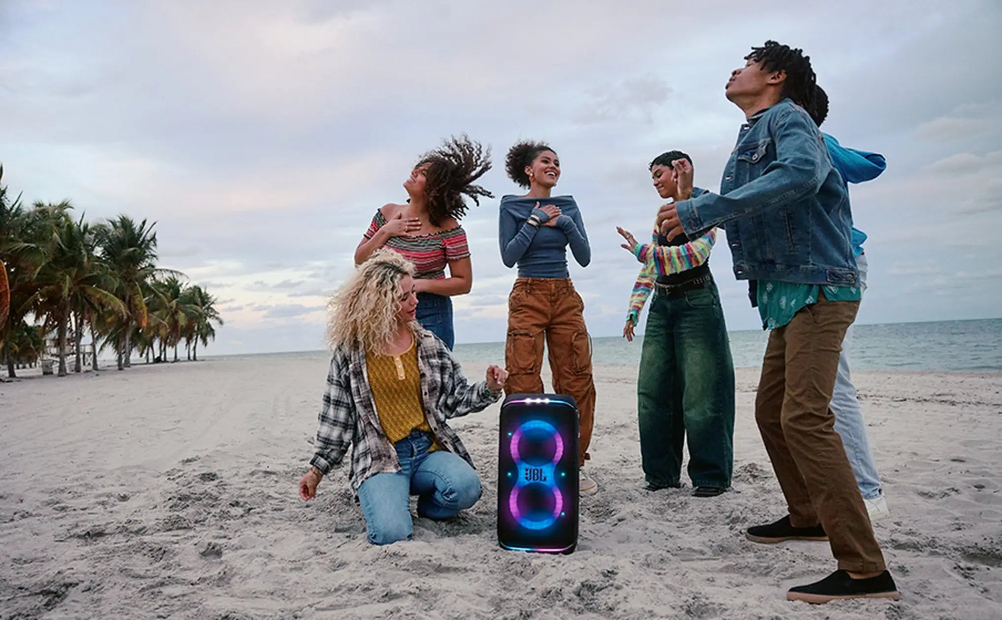 Friends dancing with JBL PartyBox Club 120 on the sand
