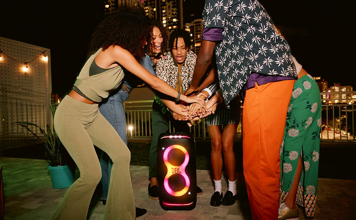 Friends gathered around JBL PartyBox Stage 320 at night