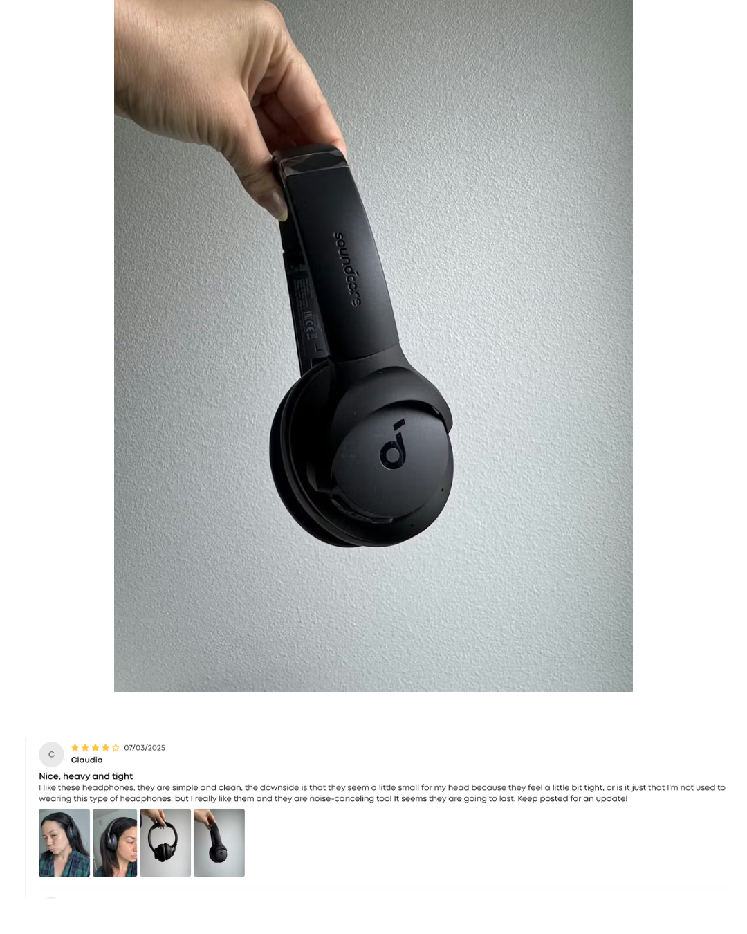 Black headphones held by a hand against a gray background