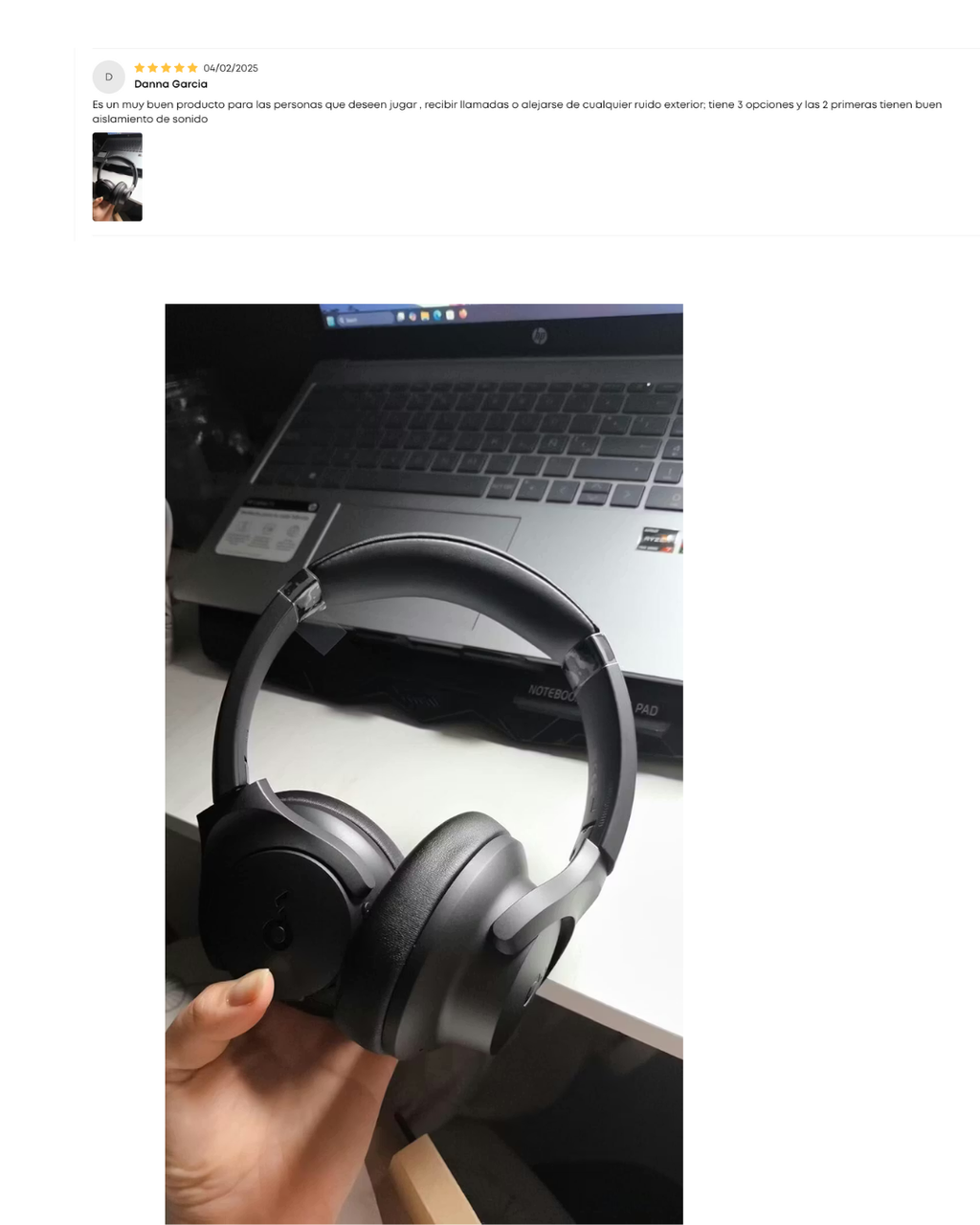 Black headphones held in front of a laptop on a desk