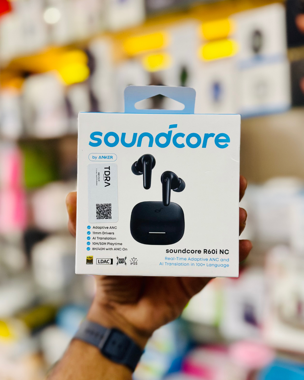 Soundcore wireless earbuds packaging held in a hand with a blurred store background